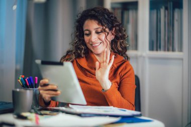 İş kadını evde dijital tablet üzerinde çalışırken iş ortağıyla görüntülü konferans görüşmesi yapıyor.. 