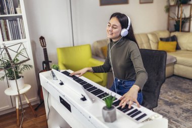 Happy girl is playing piano for her hobby relax time in home living room. Portrait Of Smiling Teenage Girl At Home Playing The Piano