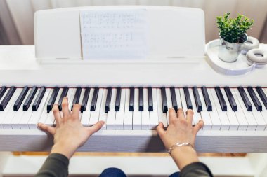 Çocuk evdeki modern elektrikli piyanoda pratik yapıyor. Müzik dersi. Yakın plan..