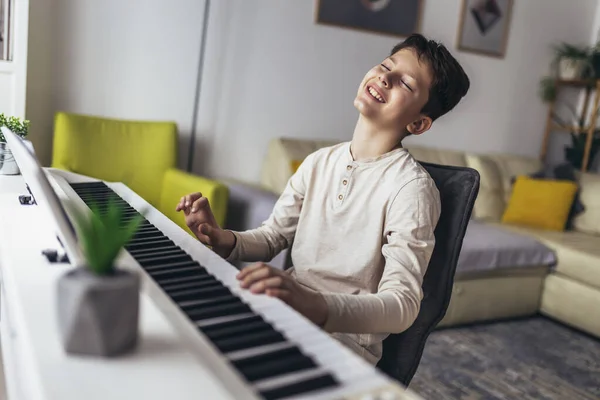 stock image Little boy playing piano in living room. Child having fun with learning to play music instrument at home.