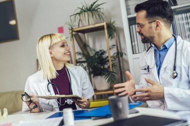 Erkek ve kadın doktor birlikte anestezi hakkında tartışırlar. Tıbbi profesyonellerden oluşan bir ekip danışmanlık yapıyor..