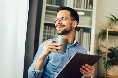 Yakışıklı gülümseyen serbest yazar evden uzakta çalışıyor ve kahve içiyor.