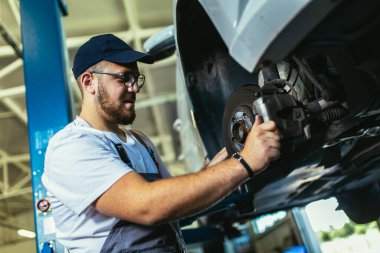 Benzin istasyonunda asansörde asılı duran arabanın yanında profesyonelce bir kontrol yap, frenleri tamir et.