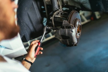 Benzin istasyonunda asansörde asılı duran arabanın yanında profesyonelce bir kontrol yap, frenleri tamir et.