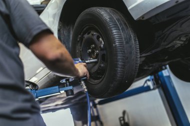 Tamircide araba çarkını değiştiren tamirci, kapat..