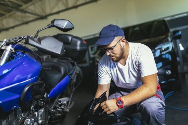 Motosiklet tamir servisinde çalışan profesyonel bir motor tamircisi.