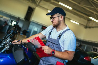 Garajda panoya yazı yazan bir adam. Motosiklet tamir servisinde çalışan profesyonel bir motor tamircisi.