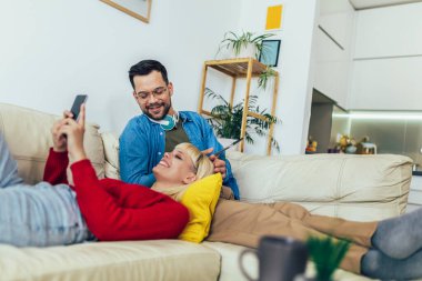 Kanepede sarılan, dijital tablet ve telefon kullanan güzel bir çift..