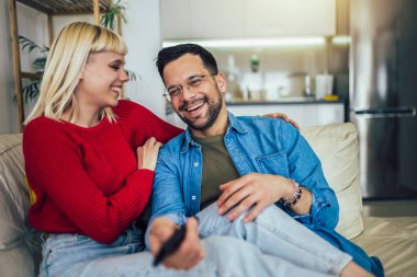 Kanepede sarılıp televizyon izleyen güzel bir çift. Aşk, mutluluk, insanlar ve eğlence konsepti.