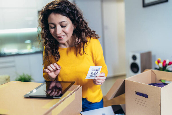 Woman affixing QR codes onto storage boxes. She is focused on her task, carefully placing the QR codes onto each box with precision. Concept organization, efficiency, or technology in storage management.