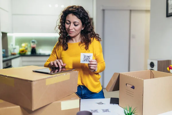 Woman affixing QR codes onto storage boxes. She is focused on her task, carefully placing the QR codes onto each box with precision. Concept organization, efficiency, or technology in storage management.