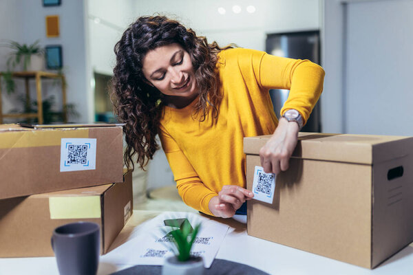 Woman affixing QR codes onto storage boxes. She is focused on her task, carefully placing the QR codes onto each box with precision. Concept organization, efficiency, or technology in storage management.