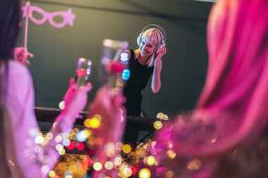 Arka planda DJ ile kulüpte dans eden bir grup insan.