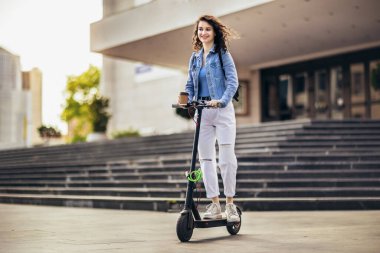 Mobiletli öğrenci dışarıda temiz havada kahve tutuyor.