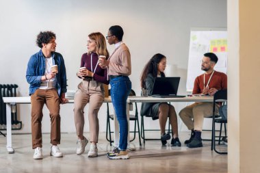 Çok yönlü çalışanlar kahkahalarla gülüyor ve kahve içiyor.