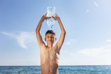The boy is having fun on the beach, getting splashed with water.