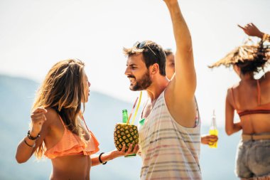 Genç arkadaşlar güneşli bir günde kumsalda eğleniyorlar..