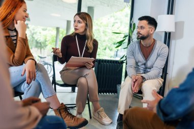 Grup, terapistin sorunları çözmeyi vurgulamasını dinliyor..