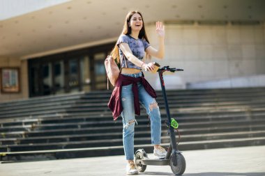 Mobiletli öğrenci dışarıda temiz havada kahve tutuyor.