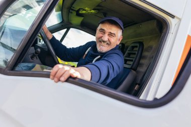 Neşeli bir teslimat şoförünün portresi beyaz kargo aracının camından dışarı bakıyor, malları arabayla getiriyor.