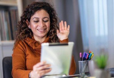İş kadını evde dijital tablet üzerinde çalışırken iş ortağıyla görüntülü konferans görüşmesi yapıyor.. 