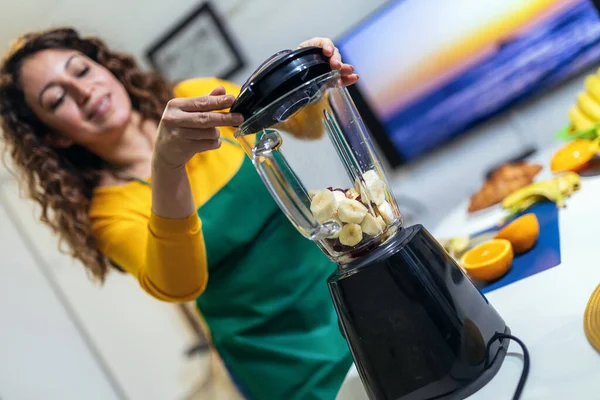 stock image Beautiful, happy young woman in casual home clothes prepares fitness cocktails with different seasonal fruits.