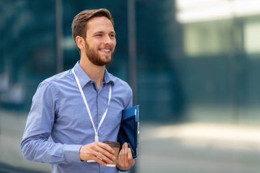 Zencefilli genç işadamı kahve içerken tabletinde çalışıyor.
