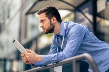 Ciddi bir işadamı işinin dışında ve bu iş için bir tablet kullanıyor..