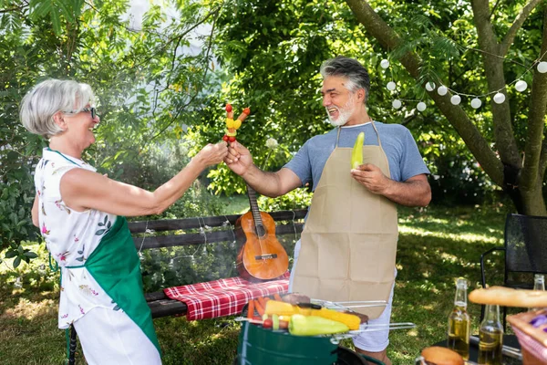 老夫婦は7月4日を裏庭で祝います 思い出をつくりながらバーベキューや野菜 飲み物を作っています — ストック写真