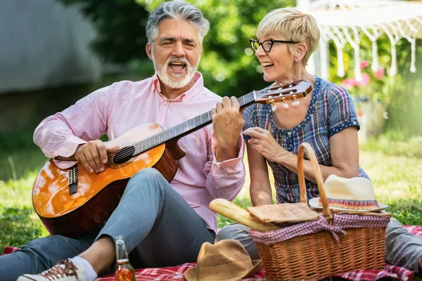 Yaşlı Bir Çift Çimenlerde Otururken Gitar Çalıp Şarkı Söylüyor Piknik — Stok fotoğraf