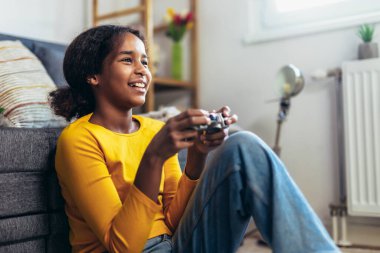 Genç Afrikalı Amerikalı kız evde video oyunları oynuyor.