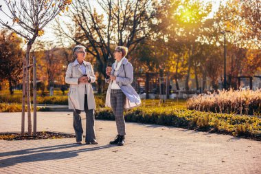 İki yaşlı kadın kahve içip konuşuyor. Sonbaharda yürüyüşe çıkıyorlar.