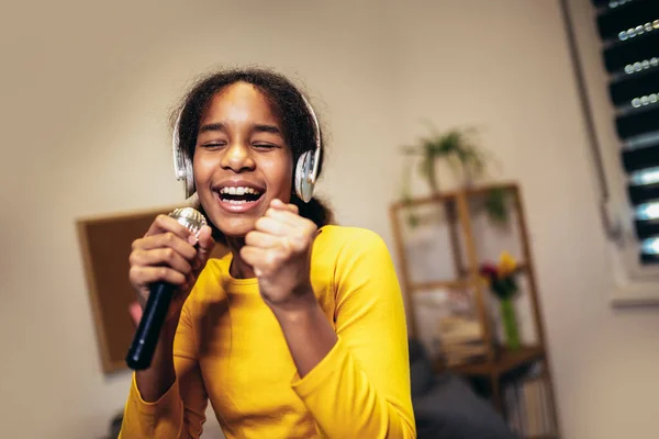 自宅でマイクの歌カラオケを開催しているかわいいPreteen黒の女の子は コンテストのための曲を記録します 子供のライフスタイルのコンセプト — ストック写真