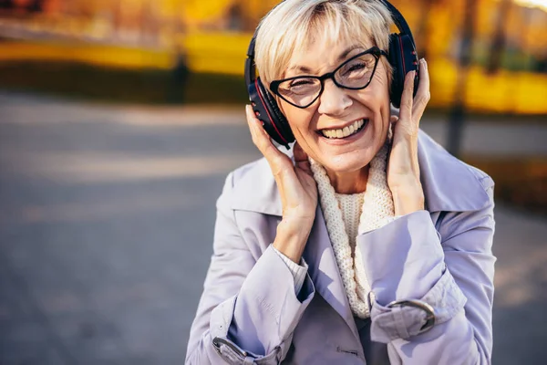 Äldre Kvinna Som Lyssnar Musik Sina Trådlösa Hörlurar Den Färgglada — Stockfoto