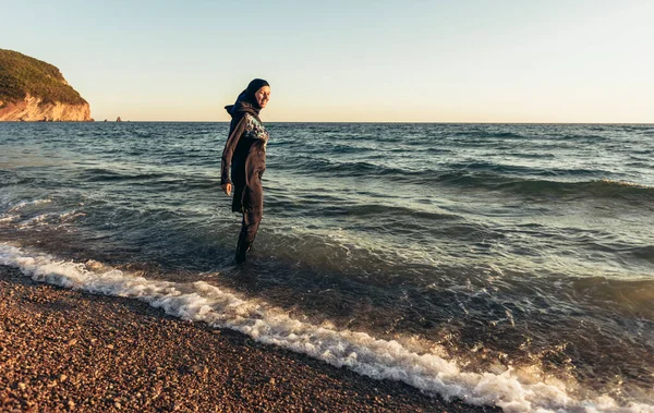 一个戴头巾的女人站在海滩上凝视着地平线 — 图库照片
