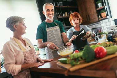 Akşam yemeği partisinde bir grup kıdemli arkadaş yemek pişiriyor..