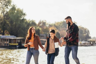 Ebeveynler ve oğulları nehir kenarında yürüyor kırsalda tatil yapıyorlar.