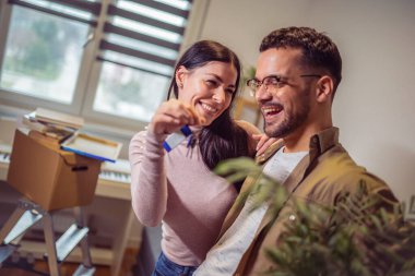 Smiling couple unpacking boxes in new home.New life.They are showing key of their new house.