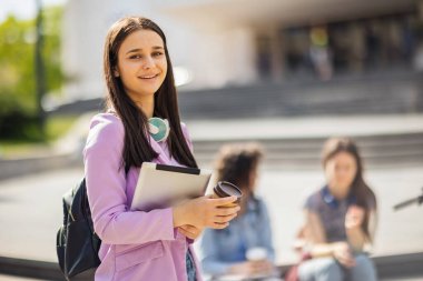 Öğrenci, arkadaşları onun arkasında çalışırken tabletinin başında dikiliyor.