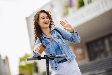 Mobiletli öğrenci dışarıda temiz havada kahve tutuyor.