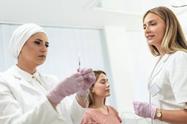 Doktor estetik ameliyatlardan önce iğneyi hazırlar.