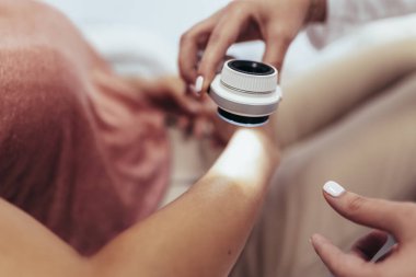 Dermatolog mol veya akne olan bir dermatoscope hastanın inceliyor. Melanom önleme