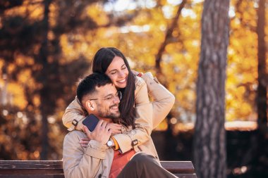 Genç çift parkta sarılıyor ve eğleniyor.