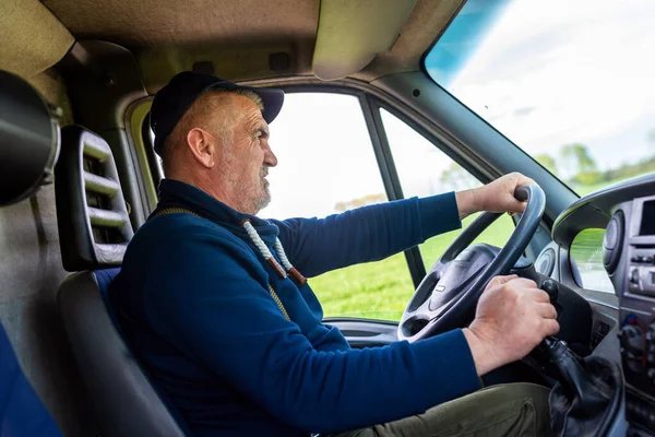 Old, confident truck driver is looking carefully at the road