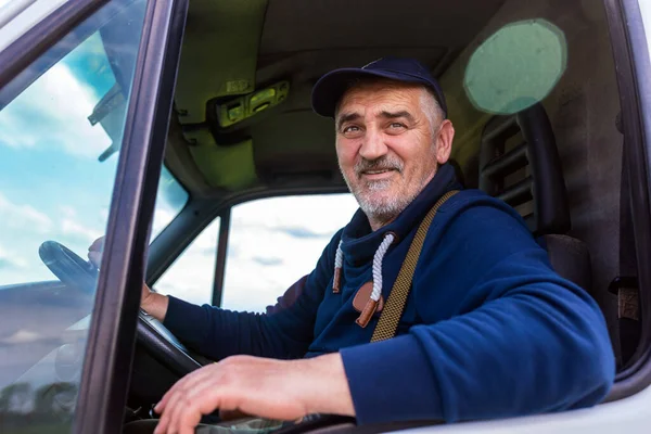 Portrait of a cheerful delivery driver looking out the window of the white cargo van vehicle, delivering goods by car