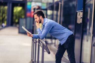 İş adamı dışarıda ve çalışmak zorunda bu yüzden dijital tablet kullanıyor. 