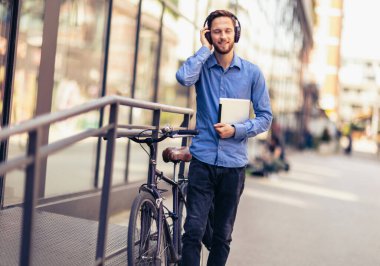 Bisikletli bir iş adamı elleri kullanarak müzik dinliyor. İş, iş ve insanların kavramları.