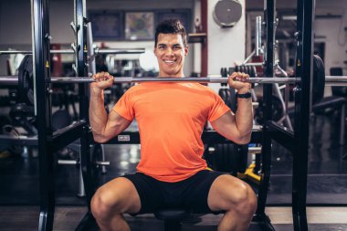 Spor salonunda egzersiz yapan yakışıklı bir genç.