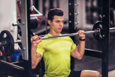 Spor salonunda egzersiz yapan yakışıklı bir genç.