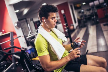 Yakışıklı sporcu dinleniyor, egzersiz yaptıktan sonra içme suyu molası veriyor.